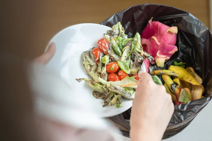 Essensreste werden in den Mülleimer geworfen